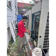 Technician working on an outdoor air conditioning system in a narrow passage