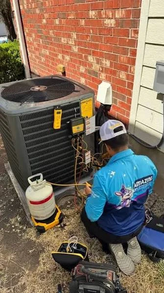 Technician servicing an outdoor air conditioning condenser beside a brick home