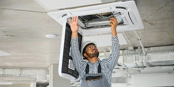 Technician servicing a ceiling-mounted air conditioning cassette