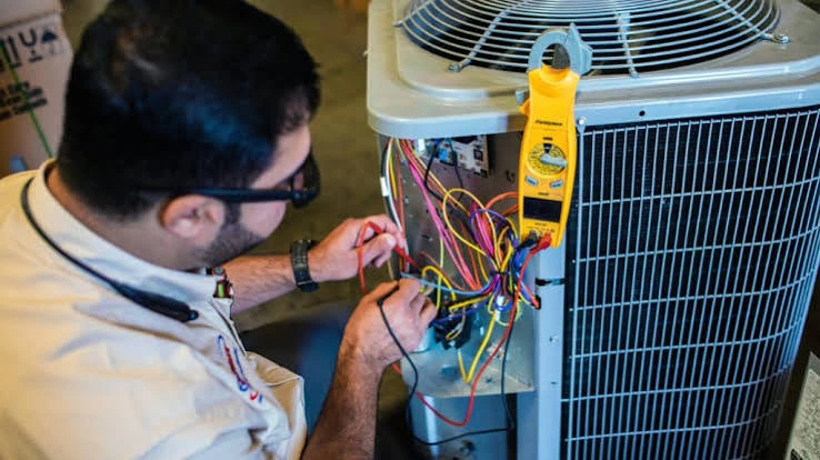 Technician checking HVAC electrical controls with a clamp meter